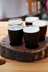 four glasses of beer sitting on top of a wooden tray