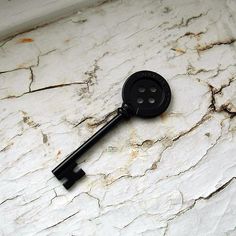 a black button on the side of a white marble counter with a key attached to it