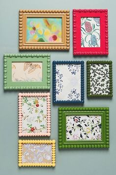 six different framed pictures on a wall with bead trimmings and flowers in them