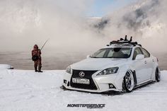 a man standing next to a white car in the snow