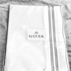 the matouik logo is placed on top of two folded white sheets with silver trims