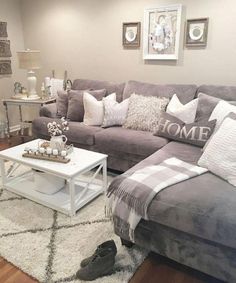 a living room with gray couches and white rugs on the floor in front of two framed pictures