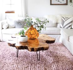 a living room with white couches and wooden table in the centerpiece, surrounded by pink rugs