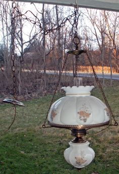 an old - fashioned hanging light fixture in the grass with trees in the back ground