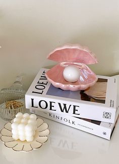 a table with two books and an egg shell on top of each other next to a candle holder