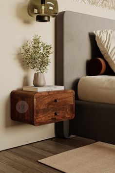 a nightstand with a potted plant sitting on top of it next to a bed