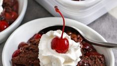 two white bowls filled with ice cream and chocolate cake pudding, one has cherries on top