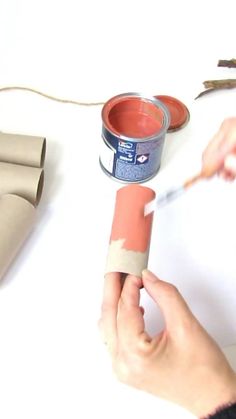 someone is painting the inside of a can with red paint and some scissors next to it