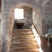 an old stone building with stairs leading up to the door and light coming in through