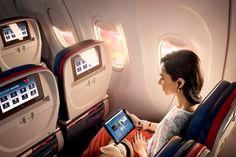 a woman is sitting on an airplane and looking at her laptop screen while she sits in the aisle