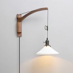 a wall mounted light with a wooden arm and white shade on the back of it