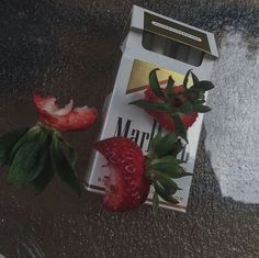 two strawberries sitting on top of a carton of milk next to a flower