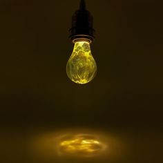 a light bulb that is lit up in the dark with yellow lights on it's side