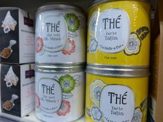 four tins of tea sitting on top of a shelf in a store display case