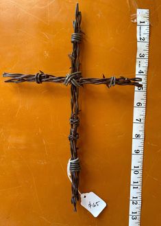 a cross made out of barbed wire next to a ruler