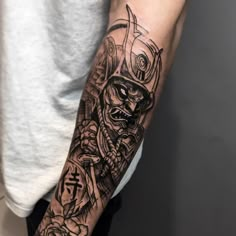 a man with a tattoo on his arm holding a knife and wearing a skull mask