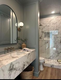 a bathroom with marble counter tops and gray walls