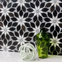 a green vase sitting on top of a white table next to a black and white wall