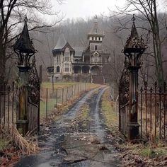 an old abandoned house is seen through the gated entrance to a dirt road in front of it