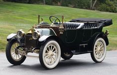 an antique car is parked on the side of the road in front of some grass