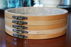 four wooden bowls with metal handles on a table