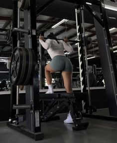 a woman squats on a weight machine