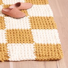 a pair of slippers sitting on top of a yellow and white rug next to a pink shoe