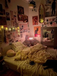 an unmade bed with yellow sheets and pictures on the wall above it in a dimly lit bedroom