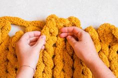 two hands crocheting the ends of a blanket