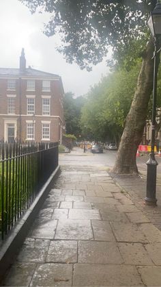 an empty sidewalk in front of a brick building on a rainy day with no people