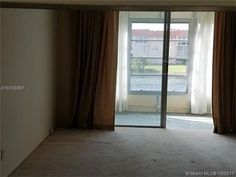 an empty room with sliding glass doors leading to a balcony and parking lot in the background