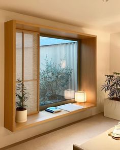 a living room filled with furniture and a large window covered in blinds next to a potted plant