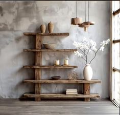 a wooden shelf with vases and candles on it in front of a concrete wall