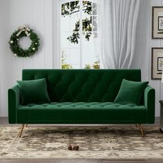 a living room with a green velvet couch and christmas wreath on the window sill