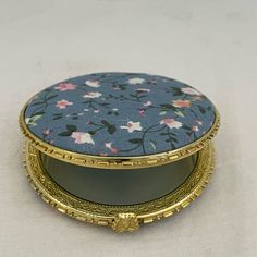 a blue and pink flowered box sitting on top of a white table