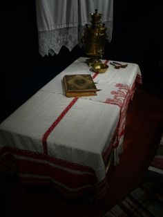 a table with a book on it next to a lamp and curtains in a dark room