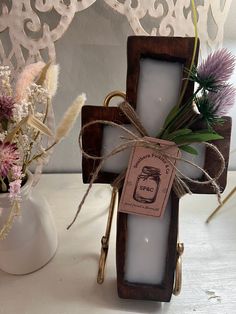 a wooden cross sitting on top of a table next to a vase filled with flowers