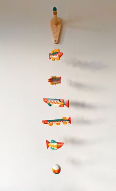 an assortment of toy airplanes hanging on the wall next to a wooden bottle and ball