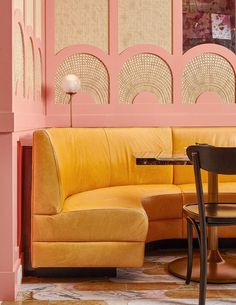 a living room with pink walls and yellow couches in the corner, next to a round dining table