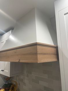 a kitchen with white cabinets and an oven hood over the stove top is made of wood