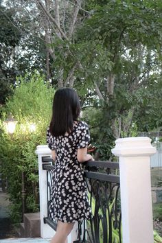 a woman is standing on a balcony looking at something in her hand as she looks over the railing