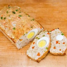 an egg and cheese sandwich cut in half on a cutting board next to two slices of bread