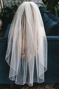 the back of a bride's veil sitting on a couch