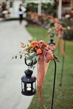 an arrangement of flowers is placed on top of a black lamp post in the grass