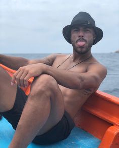 a man sitting on top of a boat in the ocean with his tongue hanging out