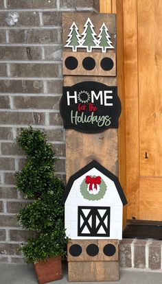 a wooden sign that says home for the holidays with a barn and wreath on it