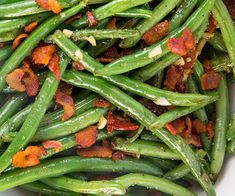 green beans with bacon on top in a white bowl