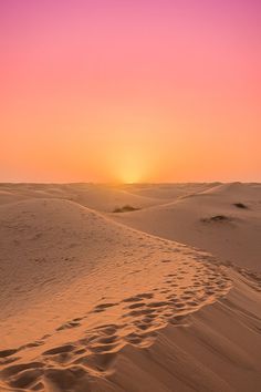 the sun is setting over sand dunes in the desert