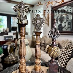 three decorative candlesticks sitting on top of a table in front of a couch