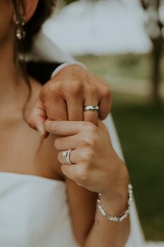 a woman in a white dress holding onto her wedding ring